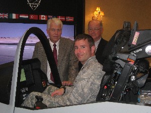 Capt. Tim Secor, USAF (c), takes a turn inside the F-35 Joint Strike Fighter cockpit simulator while meeting with Bob Kennedy (l), regional vice president, and Richard Diamond, Raytheon, at the Naval Station Newport in October.
